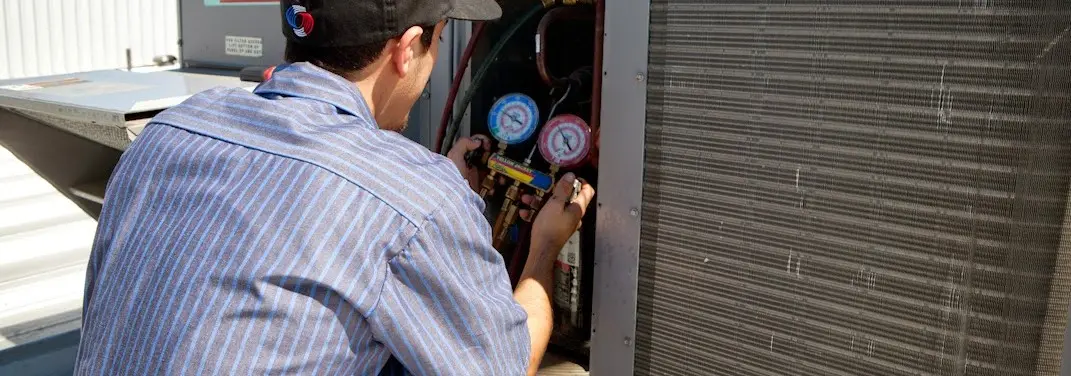 HVAC technician servicing a condenser unit in Monument